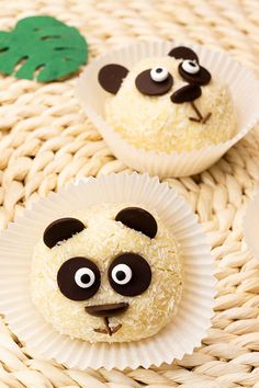 panda face cupcakes on paper plates sitting on a wicker basket with green leaves