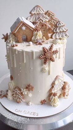 a white frosted christmas cake with gingerbread houses and snowflakes on top