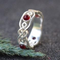 Embrace the timeless elegance of Celtic tradition with this exquisitely crafted sterling silver ring. Featuring the iconic Celtic knot symbolizing eternal love and life, this piece is accented with rich garnet gemstones, adding a touch of mystic allure. Perfect for those who cherish ancient lore and elegant design. Silver Celtic Rings, Celtic Band, Celtic Wedding Bands, Promise Rings For Him, Celtic Traditions, Red Garnet Ring, Celtic Knot Ring, Celtic Wedding, Celtic Rings