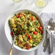 a white bowl filled with rice and veggies next to two glasses of water