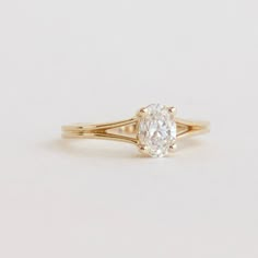 a yellow gold engagement ring with an oval cut diamond in the center, on a white background