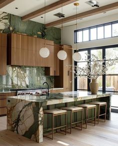 a large kitchen with marble counter tops and wooden cabinets, along with stools that match the wood flooring