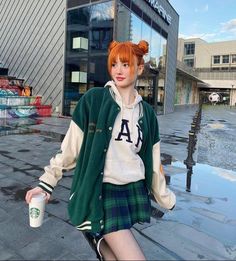 a woman with red hair wearing a green jacket and plaid skirt holding a coffee cup