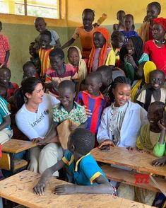 a group of people sitting around each other in front of desks with one woman smiling at the camera