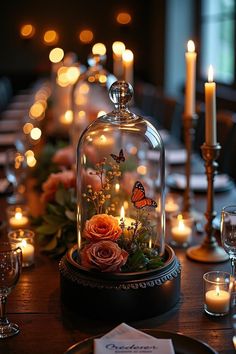 the table is set with candles and flowers under a clochet covered glass dome