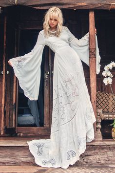 a woman in a white dress is standing on the porch with her arms spread out