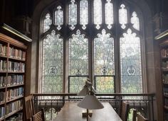 a long table in front of a large window with lots of books on the shelves