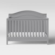 a gray crib with white sheets on it