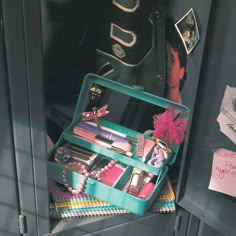 an open green suitcase filled with makeup and other items on top of a counter next to a note