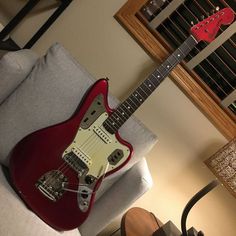 a red electric guitar sitting on top of a couch