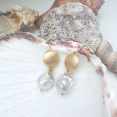 These earrings embody understated elegance and timeless beauty. A polished, gold-plated round disk forms the hook, its smooth surface gleaming with a warm, radiant glow. Suspended from this luminous disk is a single, exquisite baroque white pearl. The pearl’s organic shape, with its natural curves and unique irregularities, contrasts beautifully with the sleek simplicity of the gold. Together, the golden disk and the baroque pearl create a harmonious blend of modern sophistication and nature’s r White Gold Pearl Earrings, Forever Jewelry, Gold Pearl Earrings, Keshi Pearls, Jewelry Ring Box, Natural Curves, Men's Jewelry Rings, Understated Elegance, Gold Pearl