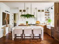 a kitchen filled with lots of counter top space and wooden flooring next to white cabinets