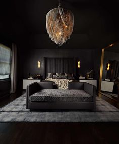 a black bedroom with a bed, mirror and chandelier