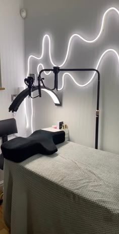 a room with a bed, chair and lights on the wall above it is lit up