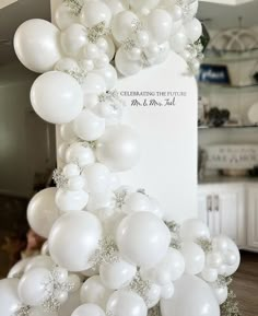 a bunch of white balloons hanging from the side of a tall column in a kitchen