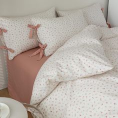 a bed with pink and white sheets and pillows on top of it next to a coffee cup