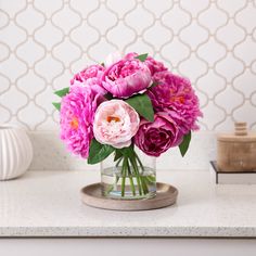 a vase filled with pink flowers on top of a counter