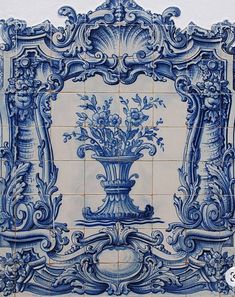 an ornate blue and white tile wall with flowers in a vase on the bottom corner