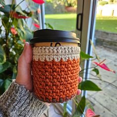 a person holding a coffee cup with a crochet pattern on the top and bottom