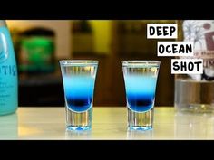 two shot glasses filled with blue liquid sitting on top of a counter