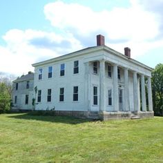 a large white house sitting on top of a lush green field