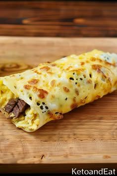 an omelet with meat and cheese on a cutting board next to a knife