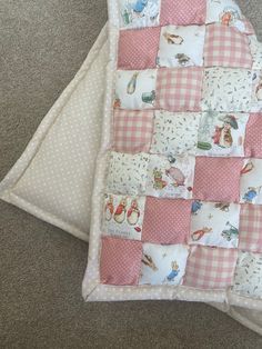 two baby quilts laying on the floor next to each other, one is pink and white