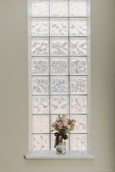 a vase filled with flowers sitting on top of a window sill next to a wall