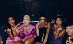 four women sitting in a tub with their mouths open and one pointing at the camera