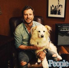 a man sitting in a chair with a dog on his lap next to an amp