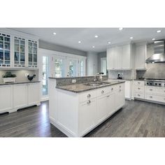 a large kitchen with white cabinets and wood floors