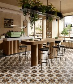 an empty restaurant with potted plants hanging from the ceiling and bar stools at the counter