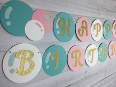 a happy birthday banner with gold glitter letters and balloons hanging from the side of a wall