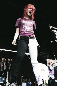 a woman with red hair and white pants on stage