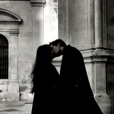 a man and woman kissing in front of a building