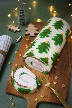 a christmas cake on a cutting board with a knife and fork next to the cake