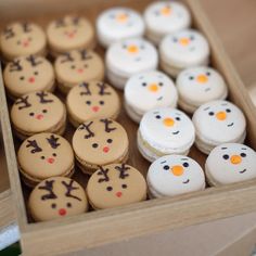 a wooden box filled with lots of small cookies covered in frosting and decorated to look like snowmen