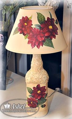 a lamp with flowers painted on it sitting on a table next to a flower vase