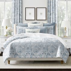 a bed with blue and white comforters in front of two framed pictures on the wall