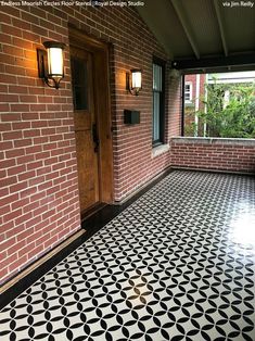 a black and white tiled floor in front of a brick wall with two lights on it