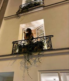 a woman is standing on the balcony looking out