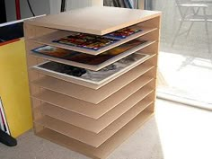 a stack of magazines sitting on top of a wooden table next to a window in a room