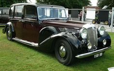 an antique car is parked on the grass