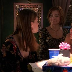 three women sitting at a table with a cake in front of them