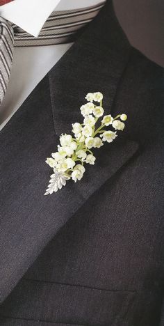 a boutonniere with white flowers is on the lapel of a suit