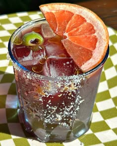 an orange slice and some ice in a glass on a checkerboard table cloth