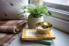 two books and a gold bowl on a window sill