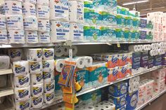 many rolls of toilet paper are on the shelves in a store with other items for sale