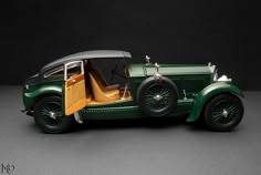 an old model green car with the door open on a black background in front of a dark backdrop