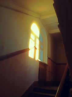 the sun shines through an open window on a staircase in front of a doorway